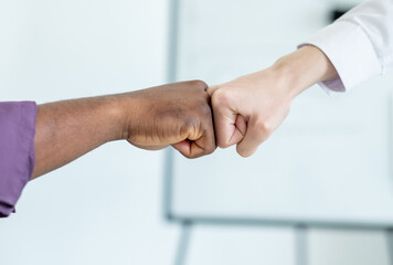 Fist bump. Team work. Business cooperation. Unrecognizable man and woman greeting mitts for good job in light room interior.