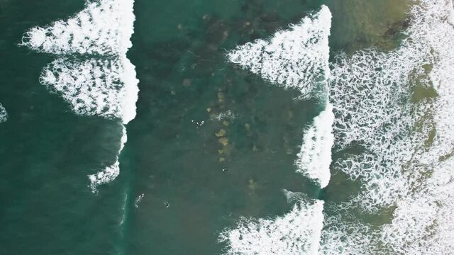 Top-down view on surfers and rolling waves.