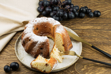 freshly baked cake on a ceramic plate on a wooden table with a bunch of wine.
