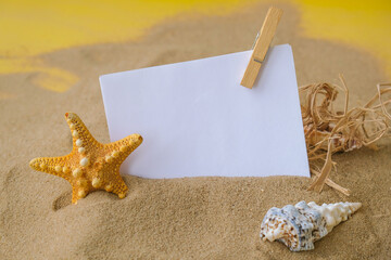 Composition sheet of paper with copy space, seashells, pebbles, mockup on sand background. Blank,...