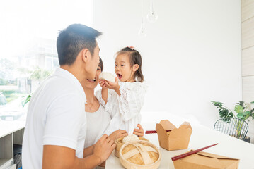 HERMOSA FAMILIA ORIENTAL JUGANDO MIENTRAS COMEN UNOS DELICIOSOS ALIMENTOS ASIATICOS 