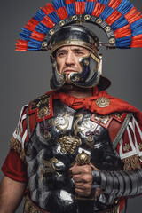 Thoughtful roman warrior dressed in steel armor and red cloak