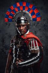 Serious legionnaire with gladius posing against dark background