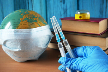 bottles and syringes of vaccine aganist covid-19 near book pile and school supplies, children...