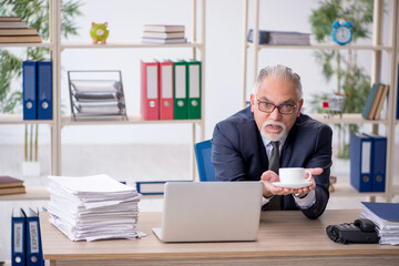 Old male employee drinking coffee during break