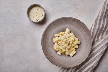 Mediterranean homemade gnocchi, prepared with potato and whole grain flour dough with cream sauce on gray concrete background. Top view. Copy space
