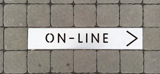 Metal sign on the sidewalk with the inscription ON-LINE