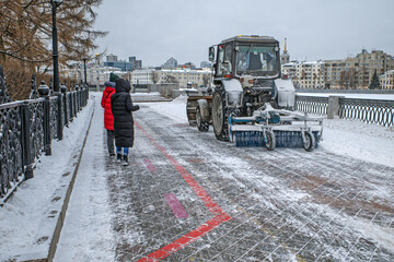 Fototapeta premium The municipal service clears the city embankment of snow on a winter day