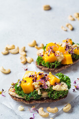 Vegan toast with cashew cheese, mango and kale. Alternative plant-based food, healthy dairy-free diet concept.