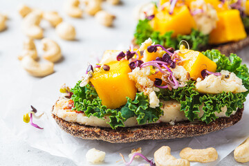 Vegan toast with cashew cheese, mango and kale. Alternative plant-based food, healthy dairy-free diet concept.