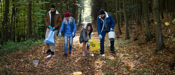 Diverse group of happy volunteers cleaning up forest from waste, community service concept.