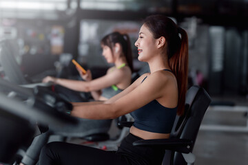 Young Asian woman working out on exercise bike at gym.