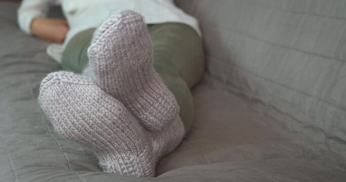Using socks in the flat. A woman use wool socks to get warm in the cold winter room.