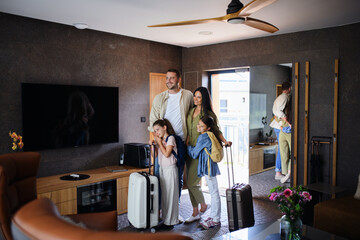 Happy young family with two children enetring room at luxury hotel, summer holiday.