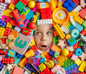 Fototapeta na wymiar Surprised little girl looking up on the abundance of toys