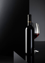 Bottle and glass of red wine on a black background.