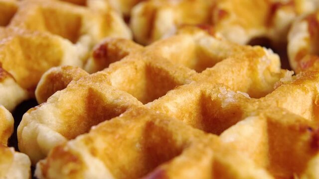 Baked round Belgian soft waffles. Macro. Slow rotation. Liege breakfast pastry dessert