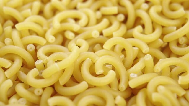 Dry yellow gobetti pasta. Carbohydrate wheat vegetarian food. Macro. Falling in slow motion. Rotation