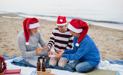 Senior couple with granddaugter celebrate New Year or Christmas and have picnic on beach.