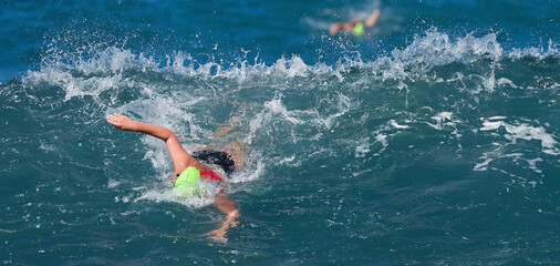 Two swimmers swimming crawl in blue sea, training for triathlon