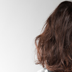 Back view of beautiful fluffy, curly medium length brunette girl. Design mockup on a gray background.