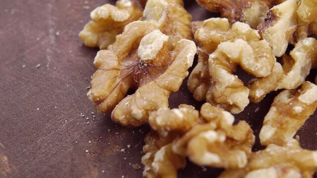 Peeled raw walnut. Dried nut kernels on a wooden surface. Macro. Slow rotation. Diet food concept