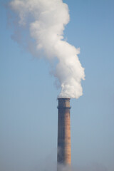 Furnace with white smoke on blue sky closeup polluting the atmosphere