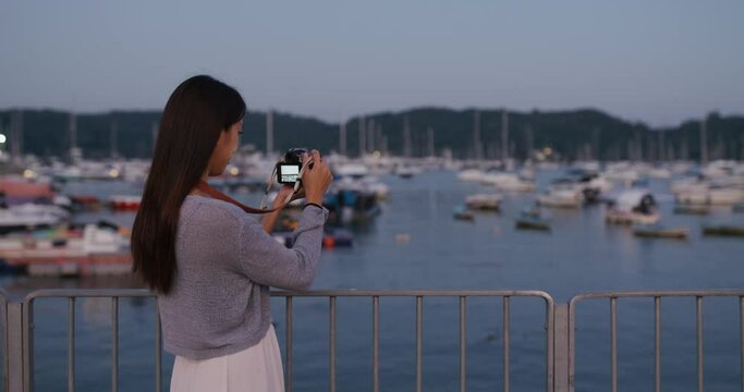 Woman use camera to take photo on the pier