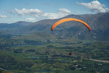 paraglider between the mountains and blue sky relaxing and enjoying the view