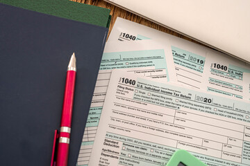 important closed notebooks red pen and tax forms 1040 lie on the desk