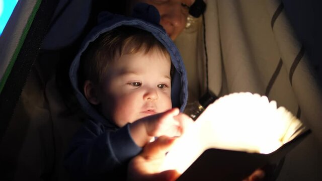 Little happy boy with mom, spend time together, sitting on a cozy tent.