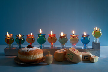 Naklejka na ściany i meble Jewish holiday Hanukkah background with oil Menorah- traditional candelabra, spinning top Dreidel and Doughnut on blue background