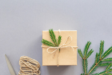 Eco-friendly packaging of christmas gift box, string and spruce branch on gray background. Zero waste, plastic free. Flat lay, copy space.