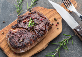 Medium rare Ribeye steak with herbs and a piece of butter on the wooden tray.