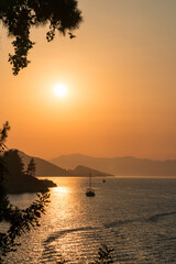 Calm sea and sunset. Sun is setting behind the hills on the horizont.  Beautiful nature background.