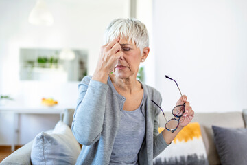 Senior woman in glasses rubs her eyes, suffering from tired eyes, ocular diseases concept