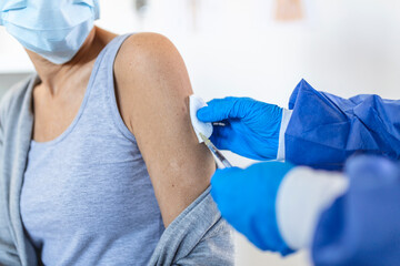 Fototapeta premium General practitioner vaccinating old patient in clinic with copy space. Doctor giving injection to senior woman at hospital. Nurse holding syringe before make Covid-19 or coronavirus vaccine.