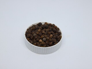 Pepper on white background. Black pepper in a white bowl.