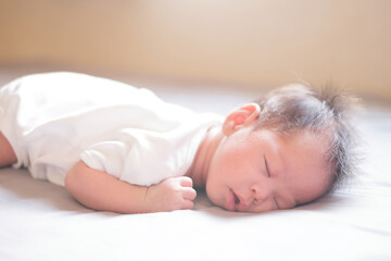Asian baby sleeping on gray bed