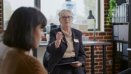 Close up of woman counselor having conversation with people in circle at aa therapy session....