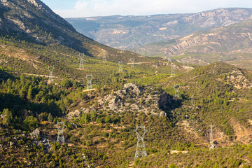 Fototapeta na wymiar High voltage electricity poles installed on opposite slopes of a deep valley. High voltage poles with high voltage wires not yet connected.
