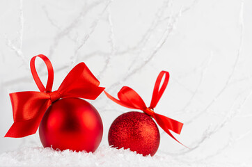 Bright christmas background - two elegant glossy glitter red balls with satin ribbon closeup in...