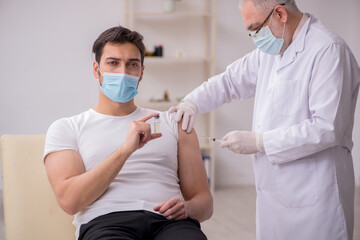 Young male patient visiting old male doctor in vaccination conce