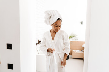 Black woman woman wearing bathrobe and towel posing at home - obrazy, fototapety, plakaty