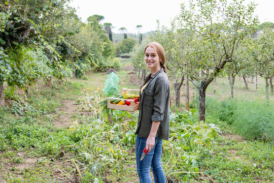 Smiling female farmer with vegetables in community garden