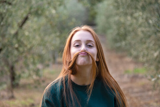 Playful woman making mustache of hair in farm