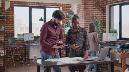 Business man with tablet talking to pregnant colleague about project planning at office. Woman expecting child and doing teamwork with employee, designing new marketing strategy.