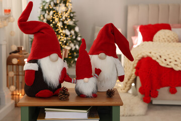 Obraz premium Cute Christmas gnomes on wooden table in room with festive decorations