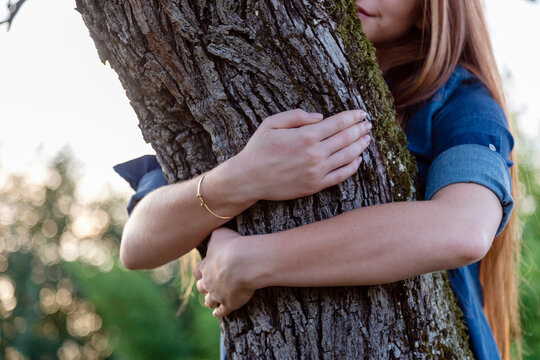 Woman hugging tree trunk at countryside