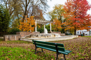 nice landscape with a bench and a fountain in an autumn park